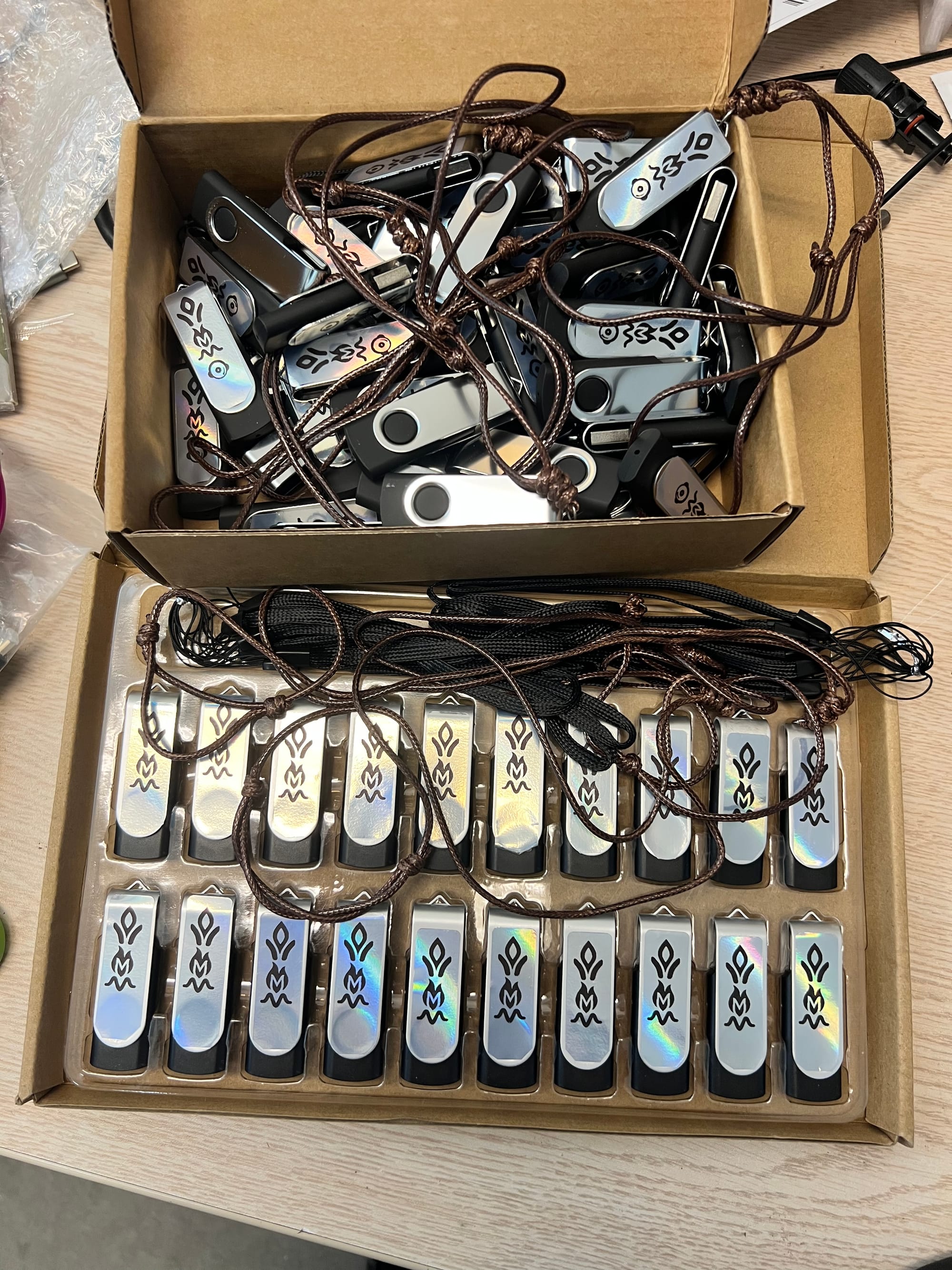 Boxes of Ashes and Echos USB necklaces, packed and ready to gift at Burning Man 2025.