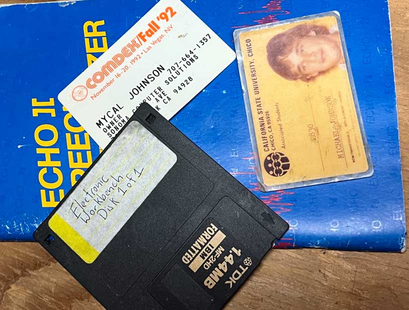 ID cards and“Close-up of a 3.5-inch floppy disk, a COMDEX Fall ’92 badge for Mycal Johnson, and a California State University, Chico student ID on a blue technical book.” Floppy found in the Attic