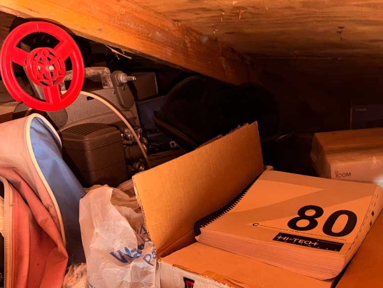 Picture of the dark corner of an attic, with 8mm projector and old compiler tools and an ICOM box